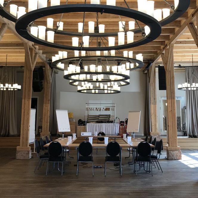 Saal im Schloss Landau mit einigen Kronleuchtern, die von der hölzernen Decke herabhängen. 