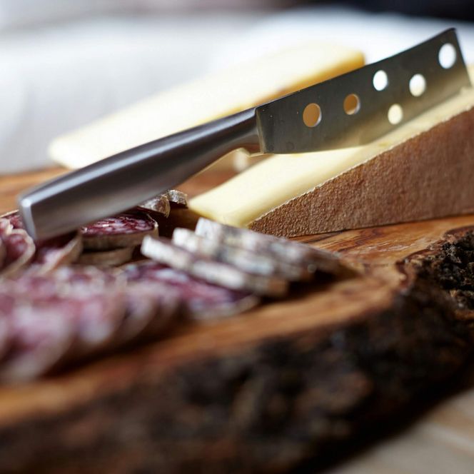 Ein Brett auf dem mehrere Salamischeiben, ein Stück Käse und ein Käsemesser liegen.