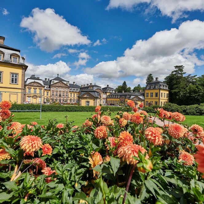 Die Aussenansicht des barocken Schlosses in Bad Arolsen, aufgenommen im Sommer, im Vordergrund orange Blumen.