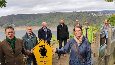 Mehrere Personen halten ein Schild vom Nationalpark im Hintergrund Edersee und Schloss Waldeck