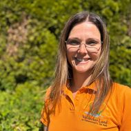 Mitarbeiterin Alexandra Zahn in einem orangefarbenen T-Shirt und mit einem Lächeln im Gesicht
