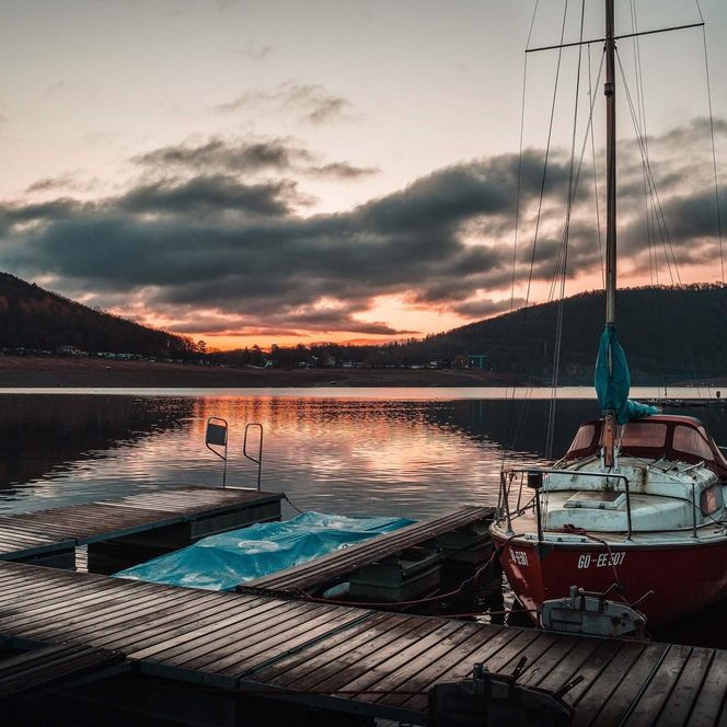 Segelboote am Steg mit Blick auf das Ufer bei Sonnenaufgang