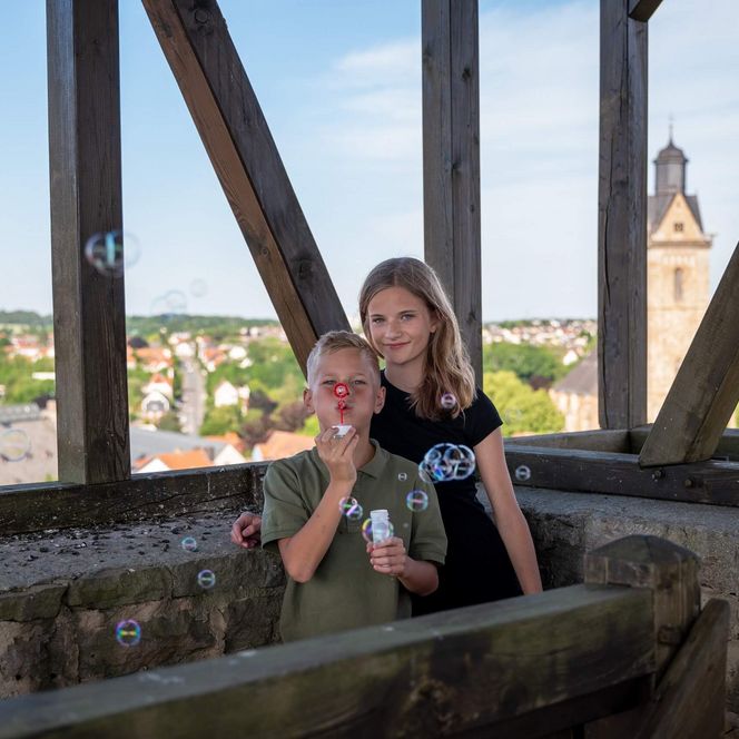 Zwei Kinder stehen im Turm-im Hintergrund die Kilianskirche und das Rathaus.