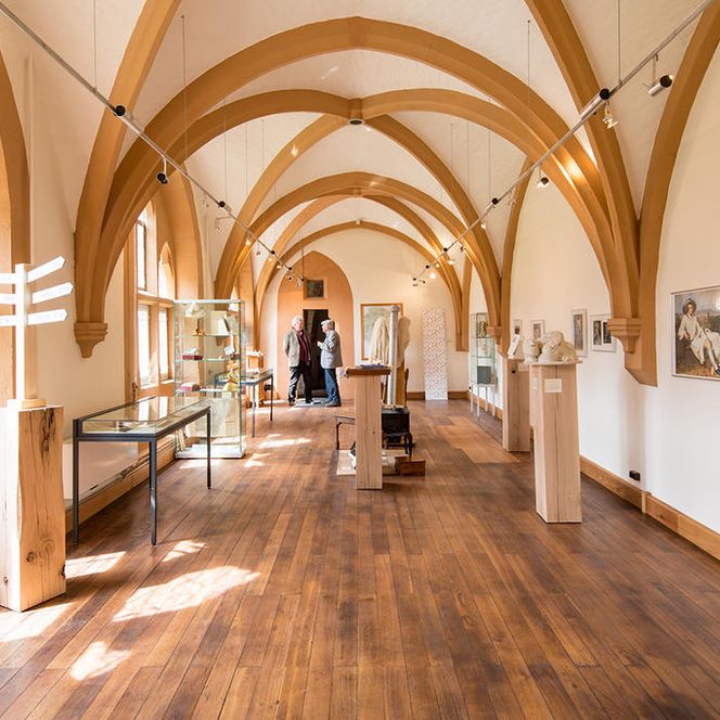 Ein Licht durchfluteter Raum in dem Bilder, Skulpturen und Ausstellungsstück präsentiert werden. 